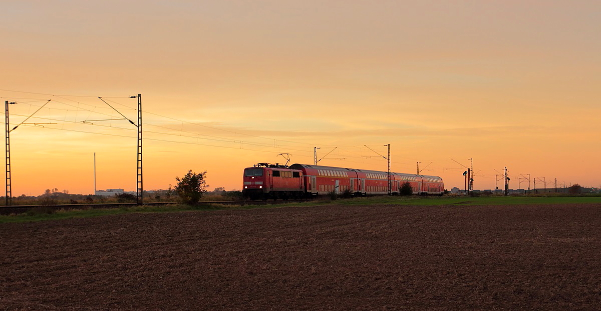 Kurz vor Sonnenuntergang fährt eine 111 mit dem RE 7 am 31.10.2014 bei Nievenheim in Richtung Süden