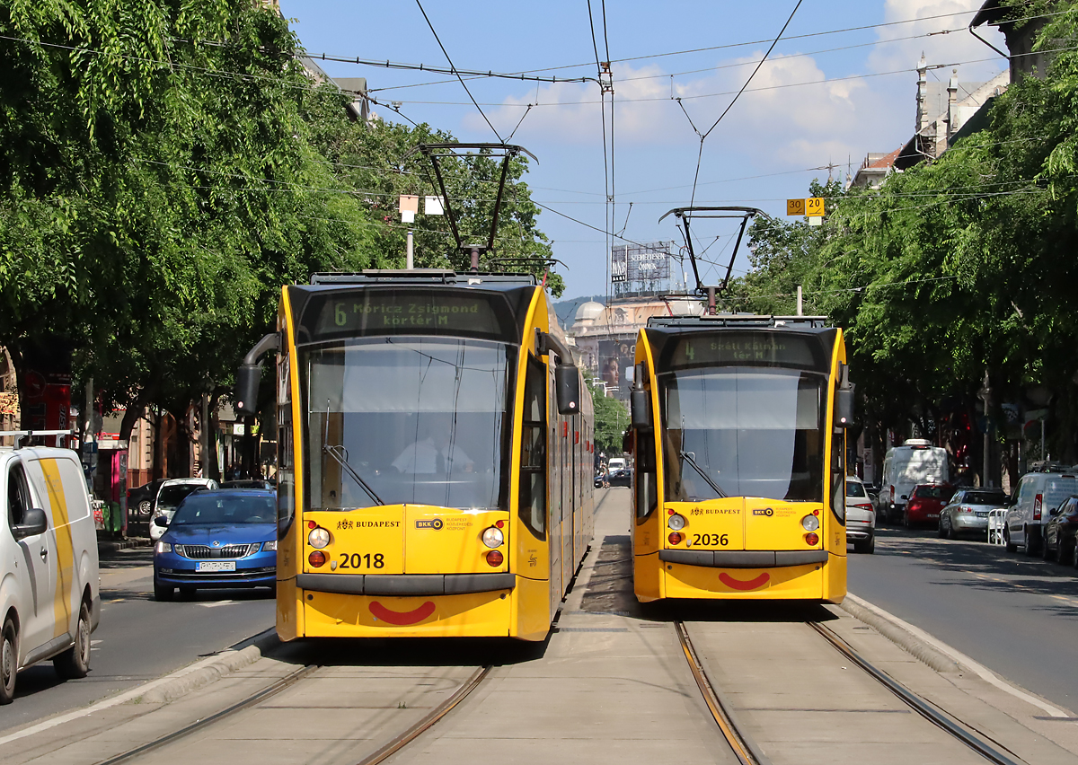 Lächeln diese Strassenbahnen? Combino - Begegnung bei der Haltestelle Oktogon M. Das Foto wurde vom Bahnsteig aus aufgenommen. Budapest, 15.6.2023