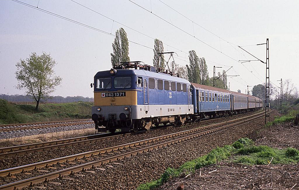 Lange Zeit beherrschte die Baureihe V 43 nahezu alle elektrifizierten 
Strecken in Ungarn und war im elektrischen Betrieb die Universal Lokomotive
der MAV. Am 13.4.1989 begegnete mir V 431371 mit einem Personenzug bei Acs 
auf der Fahrt in Richtung Gyr.