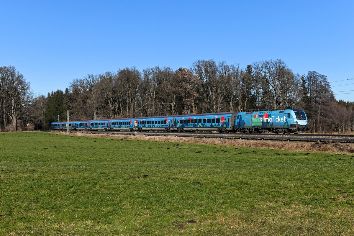 Laut ÖBB-Homepage trägt der Railjet im Klimaticket-Design die Botschaft des Klimatickets  Eins für alle  durch ganz Österreich. Die auffällige Gestaltung mit Wahrzeichen aus ganz Österreich macht den Klimajet zum begehrten Fotomotiv für Trainspotter und Bahnfreunde. Ganz so euphorisch bewerte ich das Design des Zuges nicht, aber am 16. Januar 2022 hob er sich auf der Fahrt als RJX 867 von Bregenz nach Flughafen Wien bei Brannenburg im Inntal wenigstens gut von der schneelosen Winterlandschaft ab. 