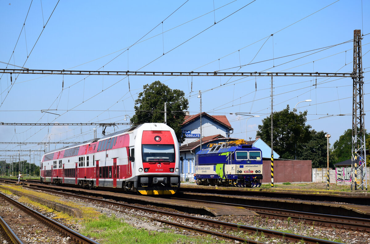 Lebensbild von Bahnhof Šaľa: Die Doppelstocktriebwagen 671 018 bei der Abfahrt in Richtung Nová Zámky. Im Hintergrund ist die 363 095  Eso : wartet auf ihrem nächsten Einsatz.
Šaľa, 14.08.2021.