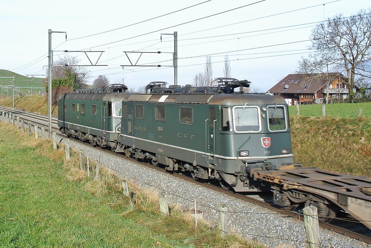 Leider von der falschen Seite kam diese mittlerweile sehr seltene Doppeltraktion... Re 6/6 11663  Eglisau  und die geschleppte Re 4/4 II 11330 mit einem Güterzug bei Einigen bei Spiez, 11.12.2015.

