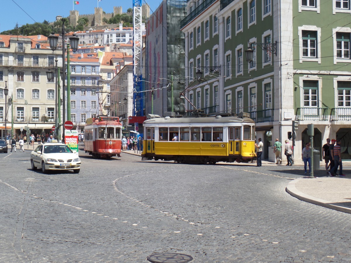 Lissabon, Praça da Figueira  (Platz des Feigenbaums) am 19.5.2015: Straßenbahnwagen Nr. 575, gelb-weiße Standard  Lackierung - beim Wechseln der Stromabnahmeart - und Stadtrundfahrtwagen, weiß-rote Lackierung, beide vom Typ Remodelados, gebaut 1935-1940, 1995/96 aufgearbeitet, Lüp 8,38, B 2,38, 50 kW, Stangen- + Bügelstromabnehmer /