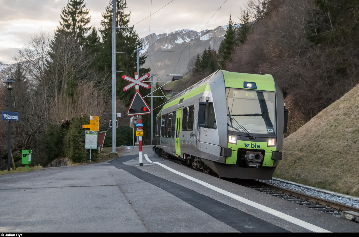 Lötschbergerin RABe 535 113 erreicht am 24. Dezember 2015 den Bahnhof Weissenburg. Interessant ist auch der Bahnübergang, welcher sich mitten auf dem Perron befindet.