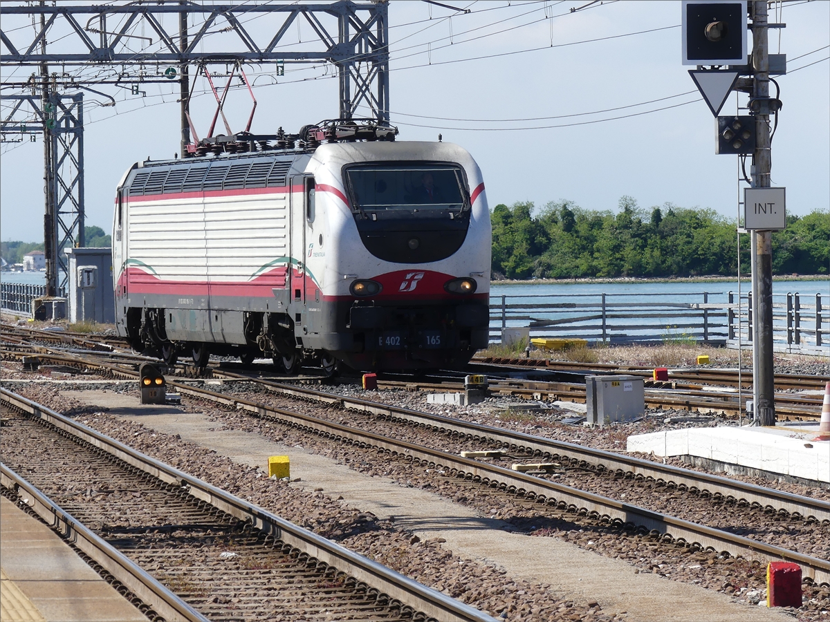 Lok E 402 165 kommt von einem Nebengleis außerhalb des Bahnhofs von Venezia Santa Lucia und setzt sich vor den eben eingefahrenen Sonderzug um diesen nachdam die Reisenden ausgestiegen sind, aus dem Bahnhof in die Abstellung zu überführen. 16.05.2019 (Jeanny) 

