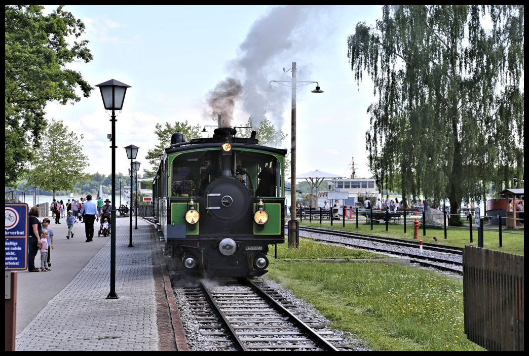 Lok Laura fährt hier am 26.5.2022 in Stock am Chiemsee mit ihrem Zug ab nach Prien.
Im Hintergrund sind die Rundfahrtschiffe am dortigen Anleger zu sehen.