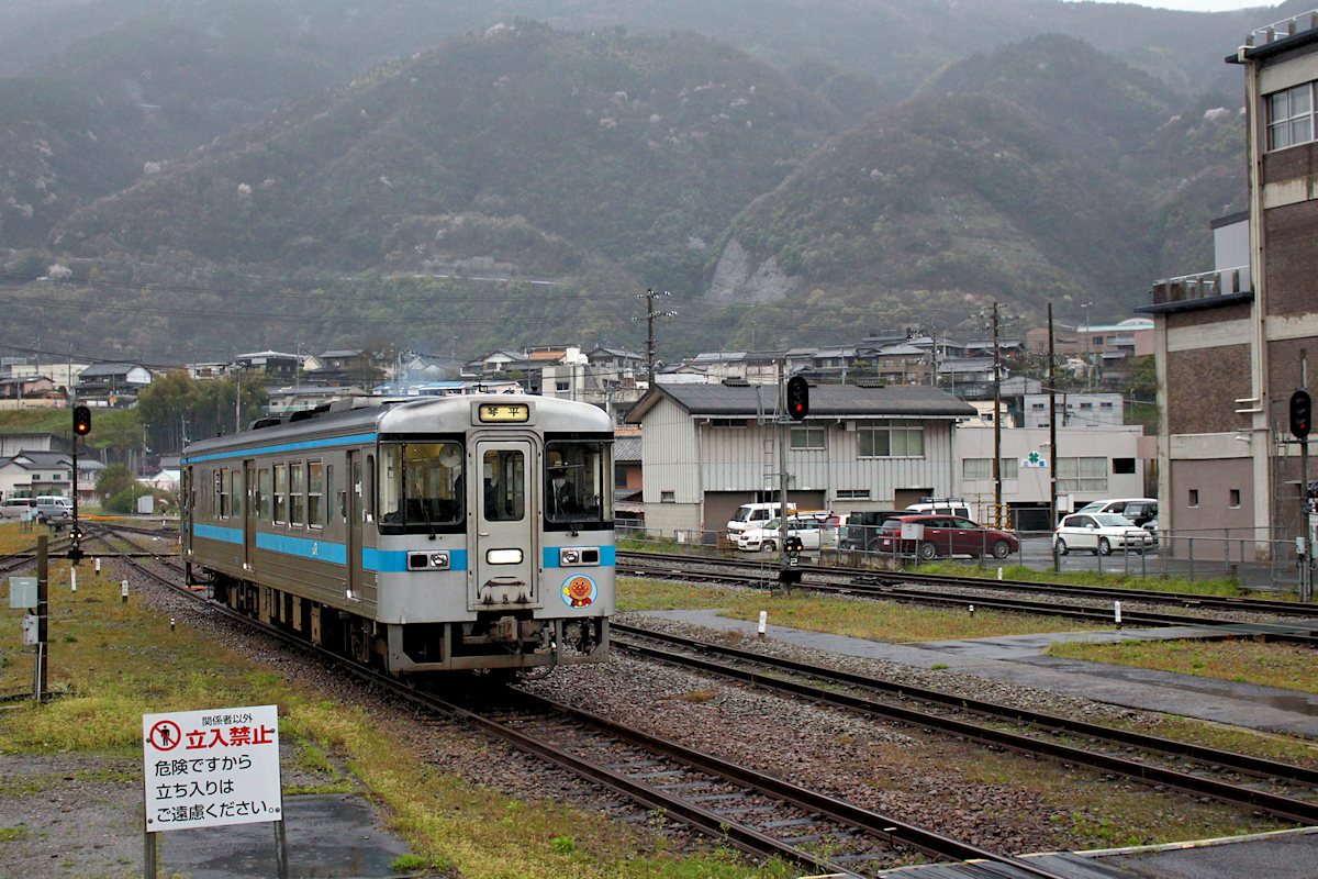 Lokalverkehr auf Shikoku - der Nordosten: Einfahrt des Triebwagens Serie 1000 Nr. 1033 in Awa Ikeda. Typische Frühlingslandschaft auf Shikoku mit Regen und blühenden Kirschbäumen in den hohen Bergen. 3.April 2015. 