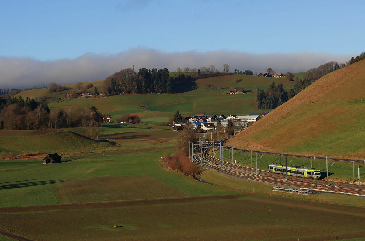 Lokalverkehr durch die Hügellandschaft Langenthal - Huttwil -Wolhusen am letzten Tag des Jahres 2021. BLS NINA 525 030 kommt vom luzernischen Hüswil und wird gleich die Kantonsgrenze (und damit die Kultur-, Konfessions-, Dialekt- und Architekturstilgrenze) in den Kanton Bern nach Gondiswil im Hintergrund überqueren. 31.Dezember 2021 