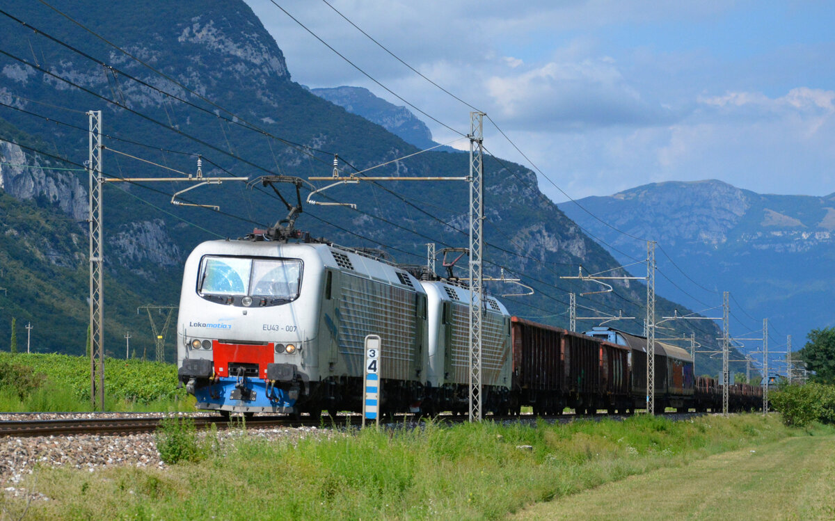 Lokomotion EU43 007 rollt mit einem Güterzug vom Brenner kommend nach Verona bei Dolcé durch das Tal der Etsch. 27.08.2021