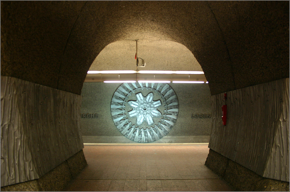 Lorenzkirche, Linie U1/11 (1978) - 

Dieser Bahnhof gehört sicherlich gestalterisch zu den ungewöhnlichsten Tunnelbahnhöfen in Deutschland. Durch seine Bauweise in der Neuen Österreichischen Tunnelbauweise (NÖT) entstanden zwei Bahnsteigtunnelröhren mit mehrern Querschlägen. Der Keller- oder Höhlencharakter wird zudem durch den grauen, groben Betonputz der Röhren unterstützt. Geschmückt wird der Bahnhof durch Nachbildungen von Rosetten der naheliegenden Lorenzkirche und durch Vitrinen mit Ausstellungsstücken eines Museums. Der Bahnhof befindet sich im Herzen der Nürnberger Altstadt und wurde 1978 eröffnet.

04.03.2006 (M)