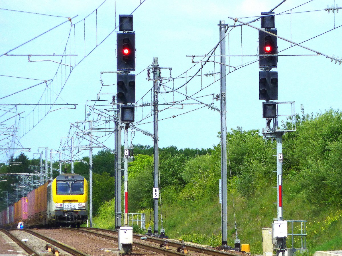 Luxemburg, Schouweiler, die SNCB HLE 1304 mit einem Containerzug ausnahmsweise auf dem linken Gleis der Linie 70 Rodange-Luxemburg via Dippach in Schouweiler. Parallel dazu ein CFL 2200 auf dem rechten Gleis nur einige Minuten später. Vom Bahnsteig aus fotografiert am 27.05.2015