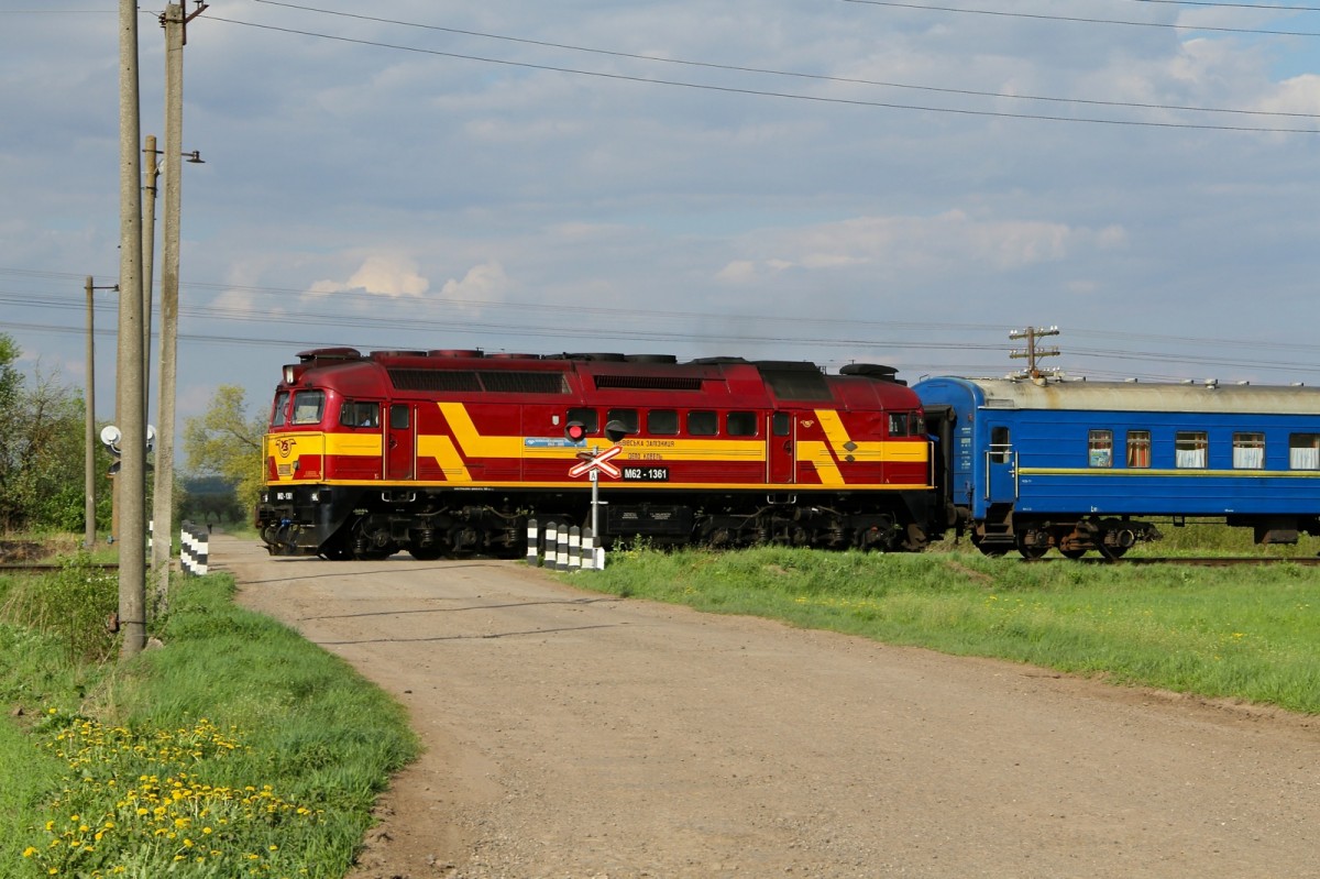 M62-1361 in einer schönen rot-gelben Bemalung auf dem Weg von irgendwo, kurz vor der Ankunft in Kolomea.
Bild am 1 Mai 2015 bei einem unbeschränktem Bahnübergang. Die Ankunft des Zuges wird ca 1 Minute mit rotem Blicklicht und lautem Gebimmel kund getan.