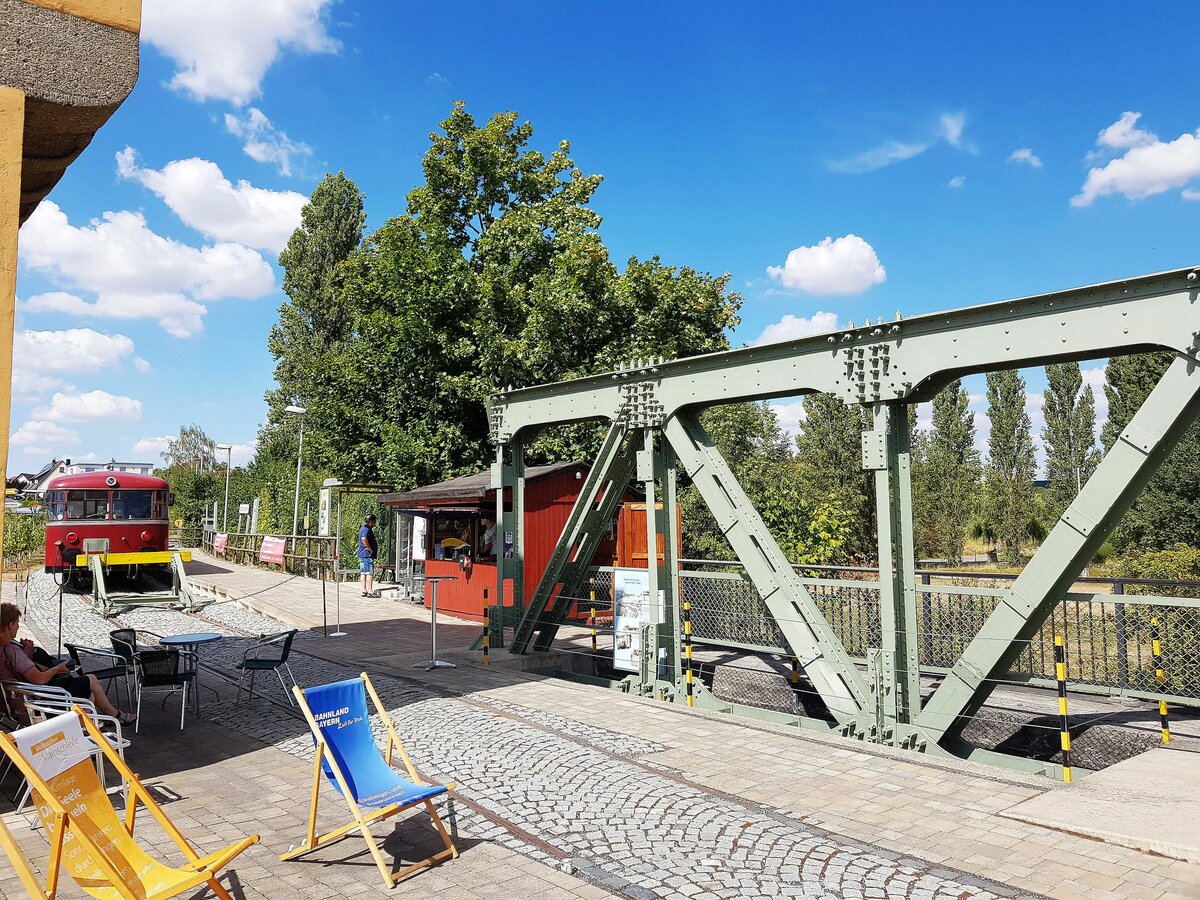 Mainschleifenbahn__Die Endstation in Volkach-Astheim. Ein kleiner Rest der kombinierten Straßen- und Bahnbrücke, die 2011 durch eine reine Straßenbrücke ersetzt wurde, ist hier als Denkmal am Bahnsteigende zu besichtigen. Diese Brücke war in zweierlei Hinsicht ein Unikum : 1947 als Behelfsbrücke aus Wehrmachtsbeständen (nachdem die Wehrmacht die Brücke wenige Tage vor dem Einmarsch der Amerikaner gesprengt hatte…) errichtet, eine stählerne Fachwerkskonstruktion der Bauart‘Roth-Waagner‘, und gemeinsame Straßen- und Eisenbahnbrücke. Roth-Waagner Pionierbrücken im Bausatz-Prinzip wurden bereits vor dem 1. Weltkrieg entwickelt.__13-08-2022 