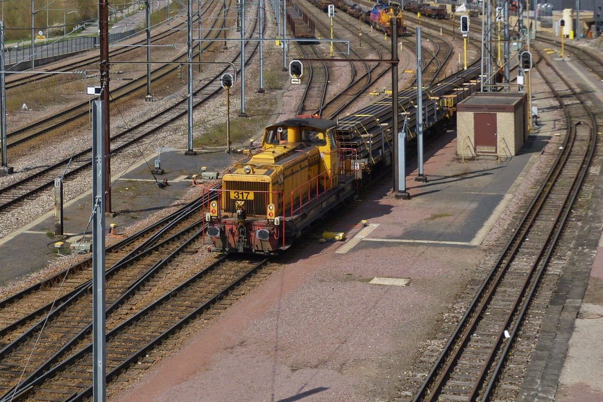 Mak Lok CFL Cargo 317, schiebt einige beladene Güterwagen durch den Bahnhof Belval Université in die Güterzugabstellung. Lokdaten: Gebaut von MaK im Jahr 1973; Typ G 850 BB; Bau Nr. 800185; Bauart: B’B‘-dh. Aufgenommen von der Überführung zum Einkaufszentrum am 14.04.2021. Lok Infos aus Loks aus Kiel.

