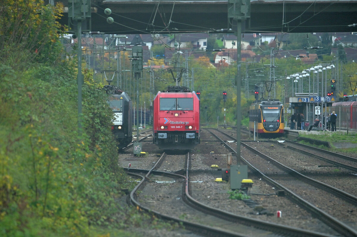 Mehrere Fahrzeuge stehen in Mosbach-Neckarelz abwartend. LZ ist im Anschnitt die MRCE 185 554-3 zusehen, nicht sichtbar ist eine der SETG 187 an der Holzverladung zugange. In der Bildmitte ist die 185 340-7 mit einer unerkannten Schwesterlok und einem Ölzug stehend und an Gleis3 ist eine AVG Triebwagen der Linie S41 zusehen der bald nach Mosbach Baden abfährt. 21.1.2022
