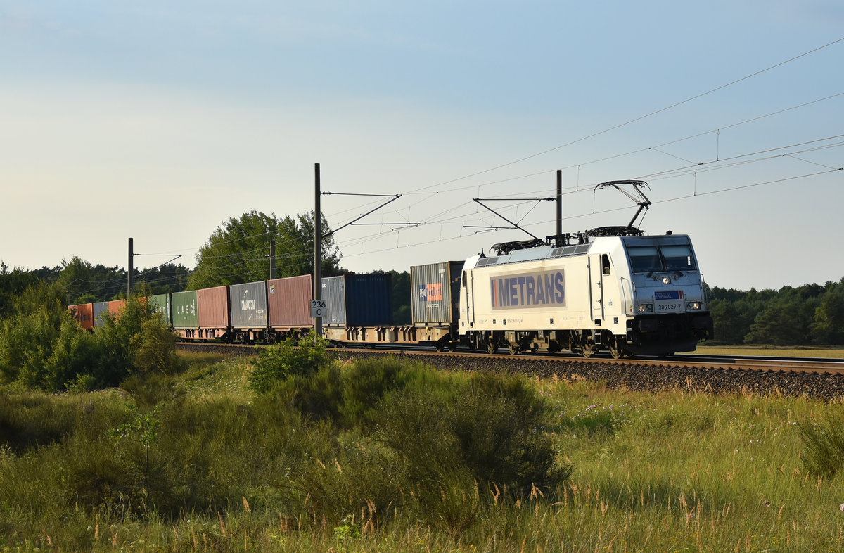 METRANS unterwegs mit einem Containerzug und der 386 027-7 in Front. Kommend aus Richtung Hamburg. 3km östlich von Büchen, 02.08.2018.