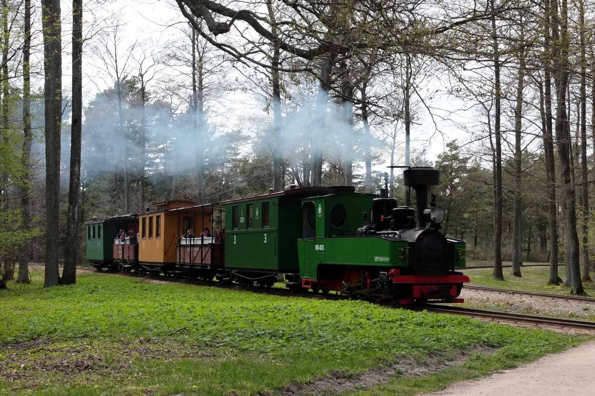 MI-631 mit ihrem Zug vor dem Bf Muzejs am 14.05.2017. Von rechts kommt das Gleis des Rundkurses unmittelbar am Freilichtmuseum Ventspils. Dieser Rundkurs ermöglicht auch zum Bf Kalns ohne Umsetzen der Lok im Bf Muzejs zu fahren, da sich in diesem Bereich ein Gleisdreieck befindet.
