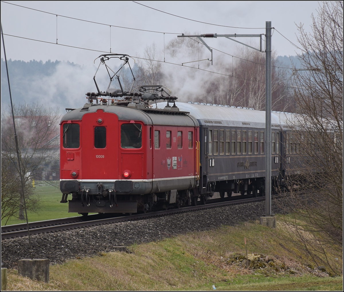Mit Dampf zum Gotthard. Bei Otelfingen ist Re 4/4 I 10009 mit Nachschieben des langen Sonderzugs beschäftigt. Birr, März 2018.