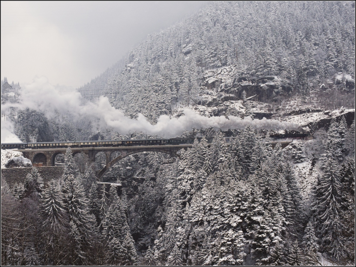 Mit Dampf zum Gotthard. Im Schneesturm zieht 01 202 zieht ihren Sonderzug die Nordrampe hoch, hier nach der mittleren Meienreussbrücke. Wassen März 2018. 