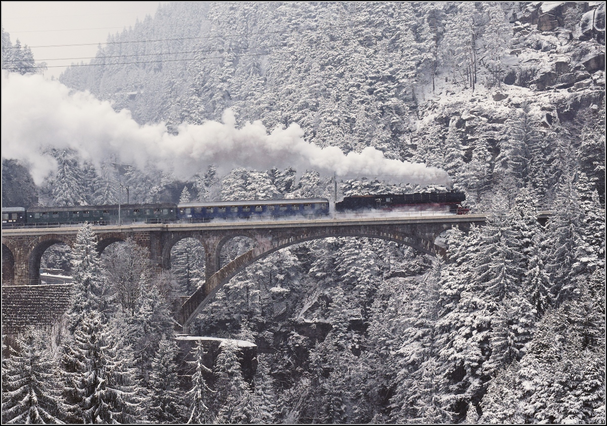 Mit Dampf zum Gotthard. Im Schneesturm zieht 01 202 zieht ihren Sonderzug die Nordrampe hoch, hier auf der mittleren Meienreussbrücke. Wassen März 2018.