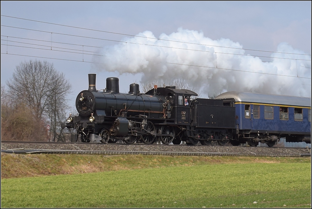Mit Dampf zum Gotthard. Im Birrfeld hat B 3/4 1367 alle Hände voll zu tun, die Steigung von Brugg nach Othmarsingen hoch mit 12 Wagen schafft die zierliche Lok nicht ohne Unterstützung durch Re 4/4 I 10009. Birr, März 2018.