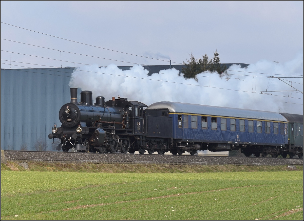 Mit Dampf zum Gotthard. Im Birrfeld hat B 3/4 1367 alle Hände voll zu tun, die Steigung von Brugg nach Othmarsingen hoch mit 12 Wagen schafft die zierliche Lok nicht ohne Unterstützung durch Re 4/4 I 10009. Birr, März 2018.