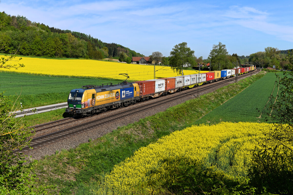 Mit dem Containerzug DGS 43933 von Dradenau nach Linz Vbf war am 11. Mai 2021 die 193 243 unterwegs. Die von der Wiener Lokalbahnen Cargo bei ELL angemietete Lok trägt eine Seitenwerbung, mit der nach neuem Personal gesucht wird. Bei Einöden in Niederbayern wurden zwei blühende Rapsfelder passiert. 