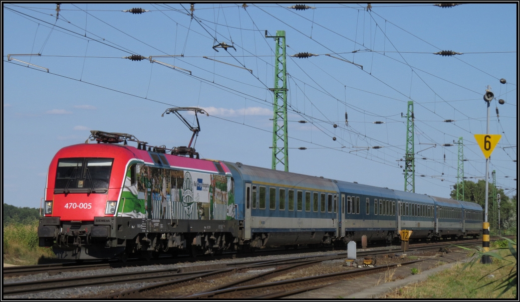 Mit dem EC Budapest-Wien am Haken ist die ungarische Taurus 470 005 der MAV am Donauufer bei Komárom unterwegs. Bildlich festgehalten Anfang August 2015.