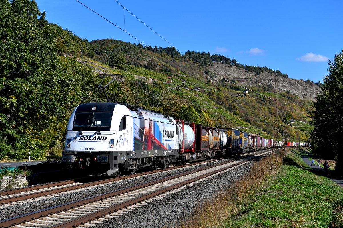 Mit dem gut ausgelasteten DGS 41150 von Budapest Soroksar Terminal to Rheinhausen kam am 04. Oktober 2018 die 1216.955 der Wiener Lokalbahn durch das Maintal gefahren. Bei Gambach konnte ich die für die Spedition Roland werbende Lok mit den frühherbstlich gefärbten Weinbergen im Hintergrund fotografieren. 