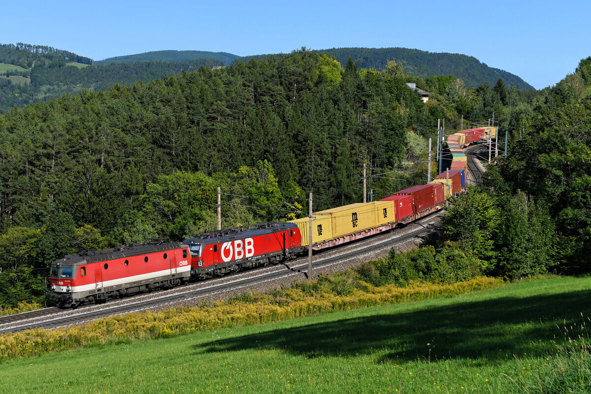 Mit dem komplett beladenen Containerzug GAG 43390 schlängelten sich am 25. September 2021 die 1144.255 und 1293.006 bei Eichberg talwärts durch die engen Bögen der Semmeringbahn. 