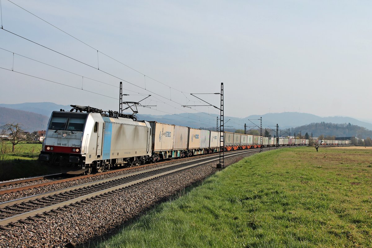 Mit dem  MOVE/EWALS Cargo -Containerzug fuhr am Nachmittag des 27.03.2020 die Rpool/LINEAS 186 446 vor dem Schwarzwald durch die Fotokurve von Kollmarsreute über die Rheintalalbahn in Richtung Offenburg.