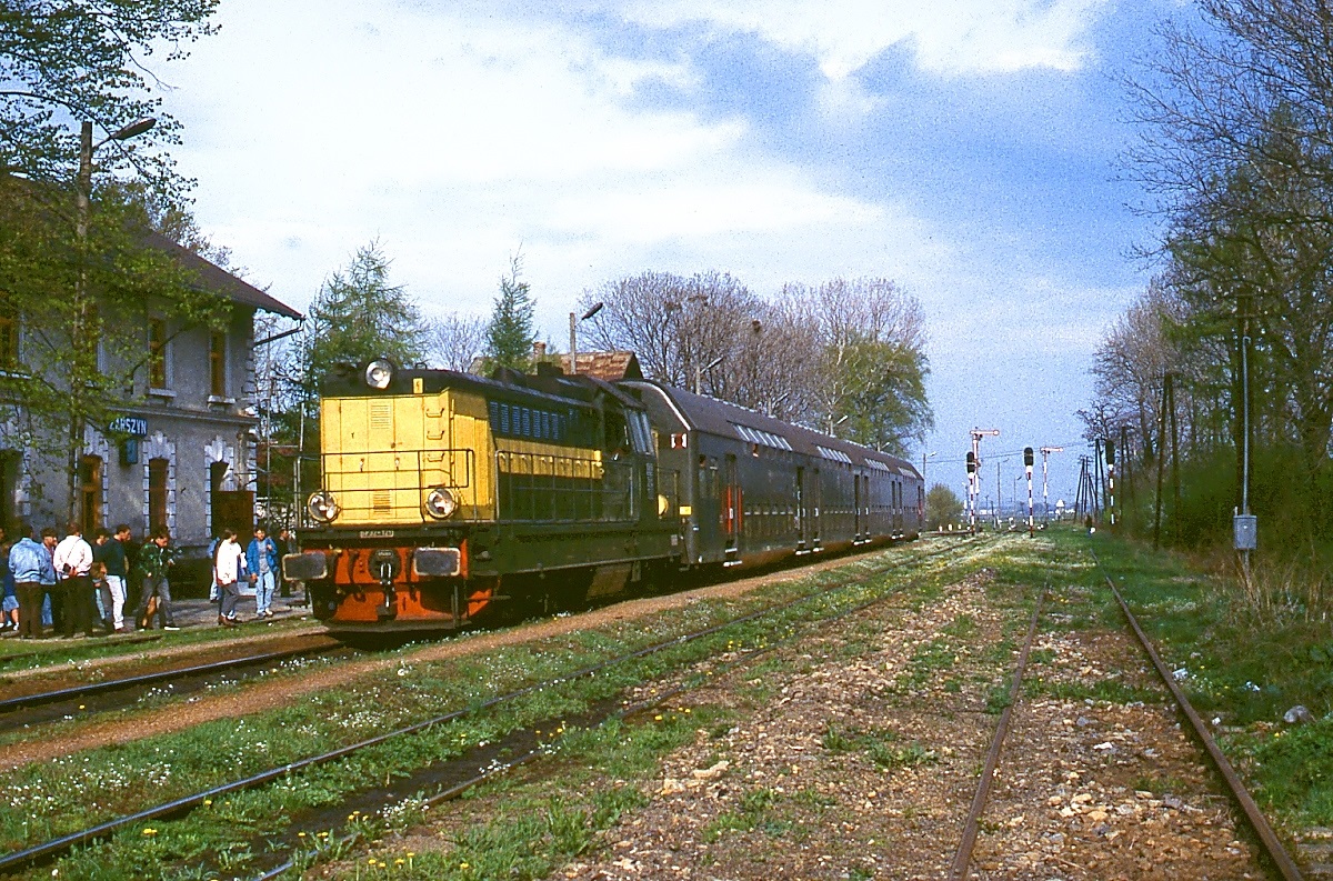 Mit einer Doppelstockwagengarnitur trifft eine unbekannte SP32 im April 1998 im Bahnhof Zarszyn ein. Der Bahnhof liegt an der Beskidenstrecke von Stroze nach Kroscienko, die als Teil der Galizischen Transversalbahn bis 1873 in Betrieb genommen wurde.