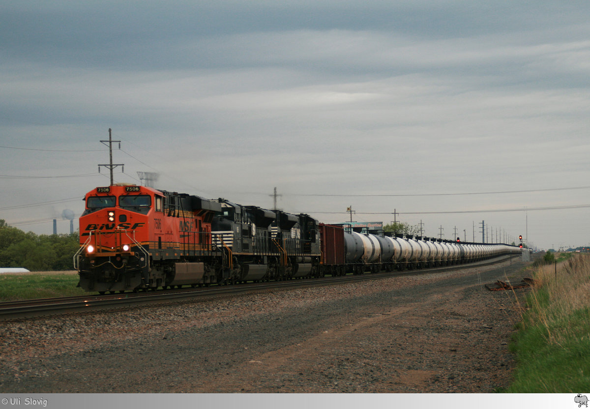 Mit einem aus mehr als hundert Kesselwagen gebildeten Güterzug sind am 9. Mai 2016 Burlington Northern and Santa Fe Railway # 7506 (GE ES44DC), Norfolk Southern # 1119 (EMD SD70ACe) und Norfolk Southern # 1122 (EMD SD70ACe) in Minnesota unterwegs.
