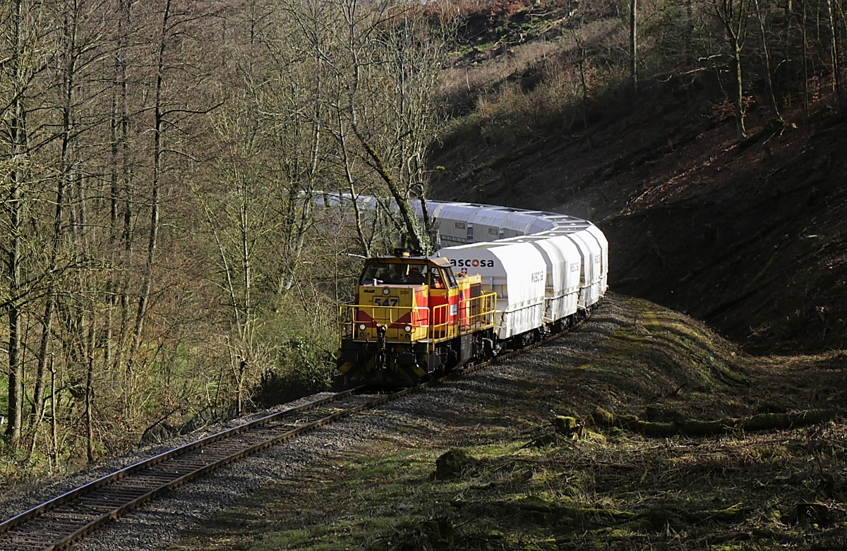 Mit einem beladenen Kalkzug schlängelt sich die ThyssenKrupp-Lok 547 am 17.03.2020 zwischen Auermühle und der Papierfabrik durch das Angertal (Bildausschnitt)