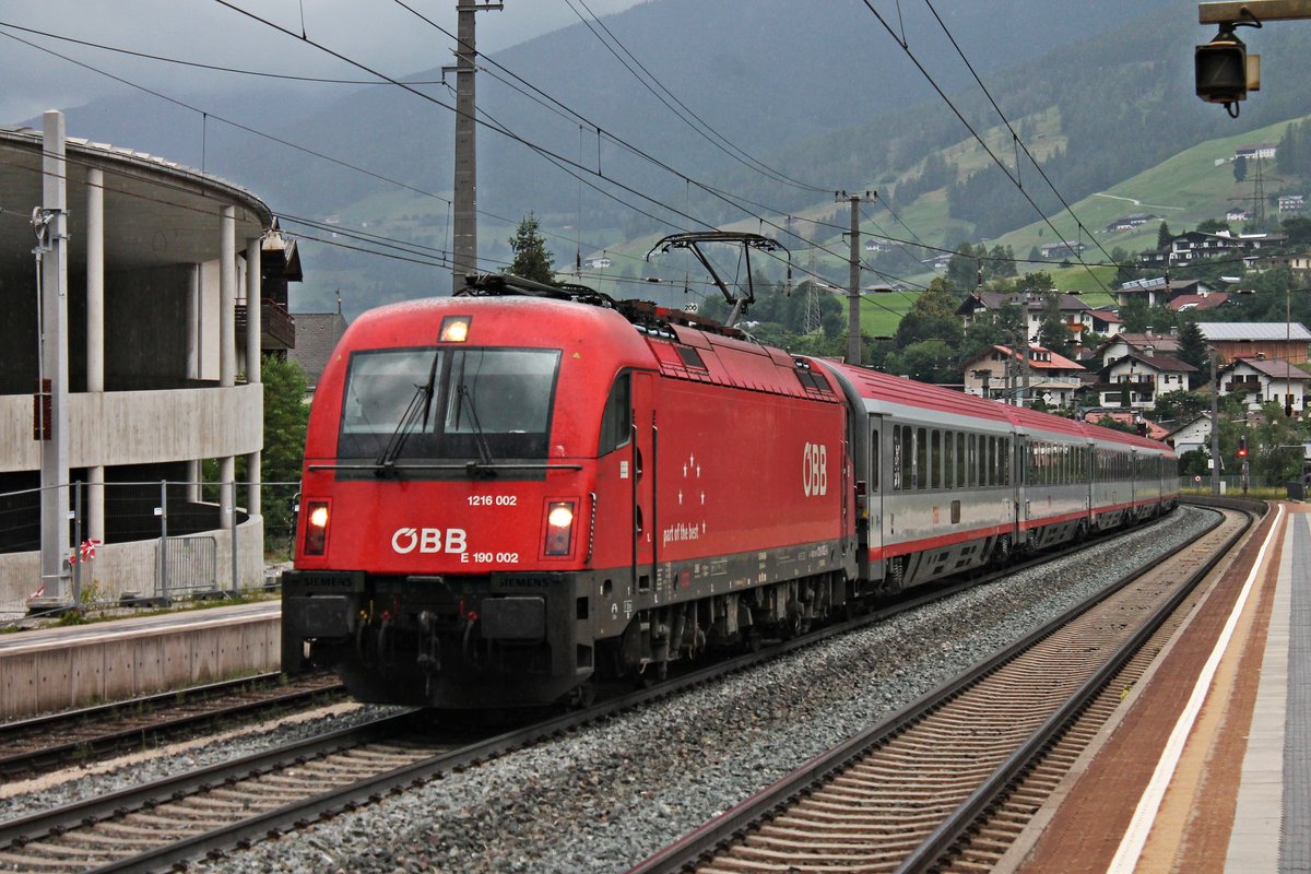 Mit einem EuroCity nach Italien fuhr am Mittag des 03.07.2018 die 1216 002 (E 190 002) kurz vor einem Regenschauer durch den Bahnhof von Matrei am Brenner in Richtung Brenner.