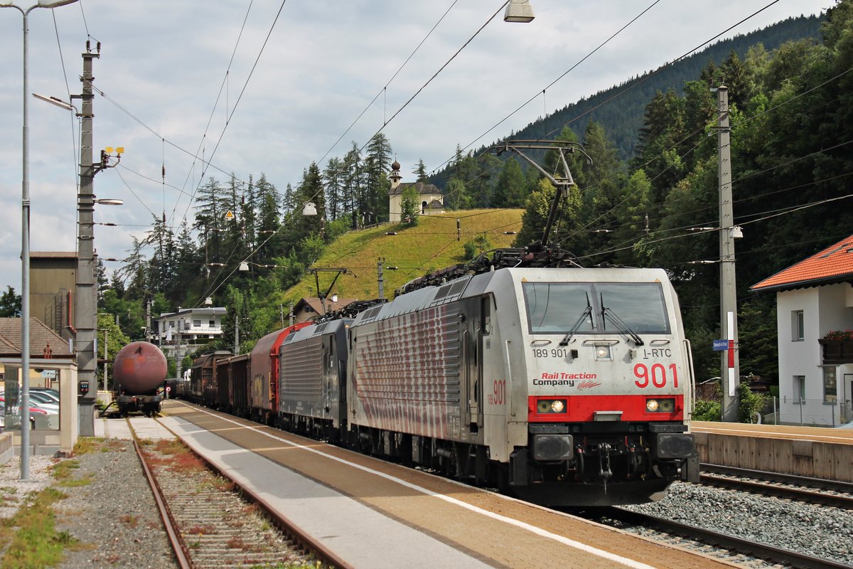 Mit einem gemischten Güterzug nach Italien fuhr am Morgen des 04.07.2018 die 189 901 zusammen mit MRCE/LM ES 64 F4-009 (189 909-5) durch den Bahnhof von Steinach in Tirol in Richtung Brenner. Im Hintergrund ist die Kalvaienberg Kirche zu erkennen.