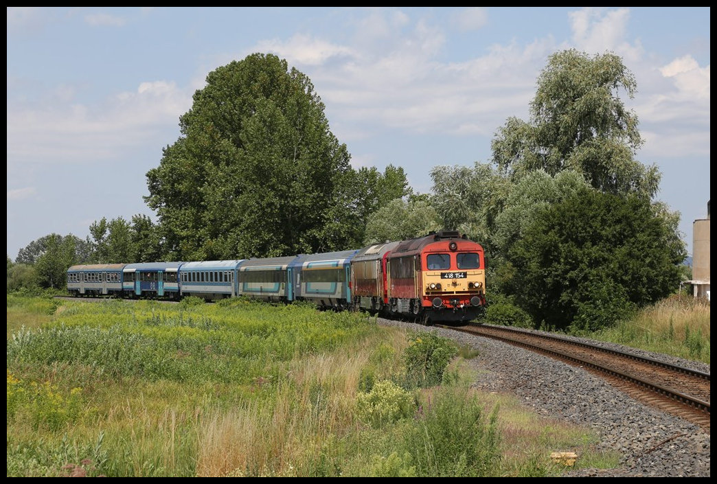 Mit einem IC nach Budapest nähert sich hier am 16.7.2022 um 13.44 Uhr die MAV 418154 dem Haltepunkt Nemesgulacs Kisapati. Hinter der Lok läuft leider verdeckt die Nostalgie Diesellok 40.2103 mit.