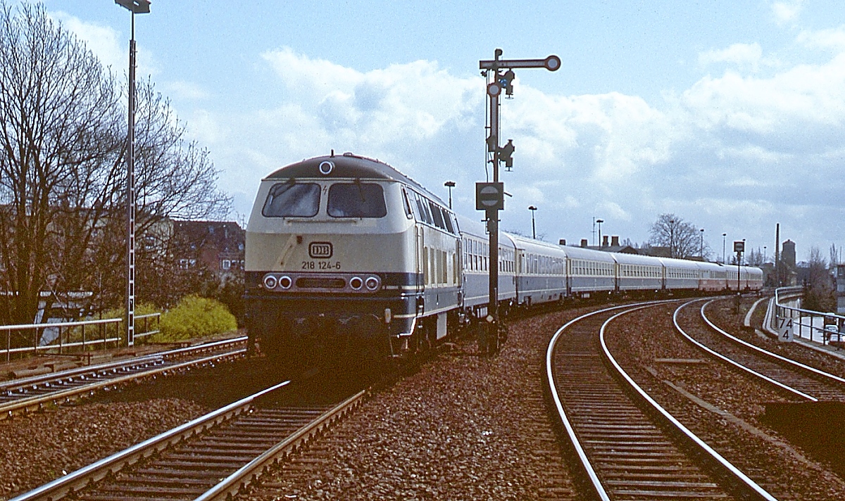 Mit einem Intercity nach Westerland fährt 218 124-6 am 27.04.1985 in den Bahnhof Neumünster ein. Abgenommen wurde die Lok am 09.12.1971 in Flensburg, ausgemustert am 07.10.2004 in Darmstadt.