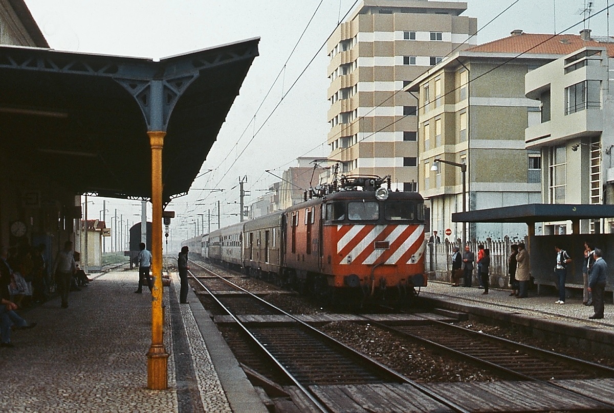 Mit einem langen Personenzug trifft eine Lok der Reihe 2500 am 28.04.1984 im Bahnhof Espinho südlich von Porto ein. Die CP beschaffte 1956 bei Alsthom 15 dieser Lokomotiven, die letzten wurden 2009 abgestellt. Der oberirdische Betrieb endete hier 2008, nachdem die Bahnstrecke in einen Tunnel gelegt wurde.