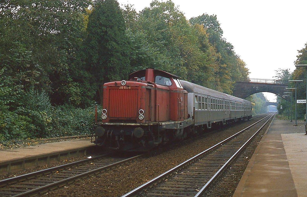 Mit einem Nahverkehrszug von Solingen-Ohligs nach Wuppertal-Oberbarmen fährt 212 324-8 an einem Herbsttag Anfang der 1980er Jahre in Solingen-Schaberg ein