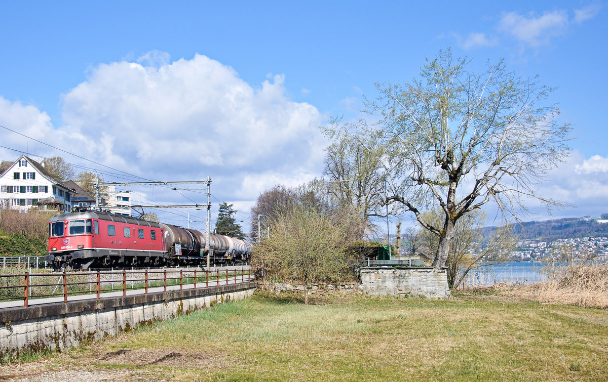 Mit einem Ölzug legt sich die Re 620 056-2 entlang des Seeuferwegs zwischen Au ZH und Wädenswil in die Kurve. 06.04.2021.