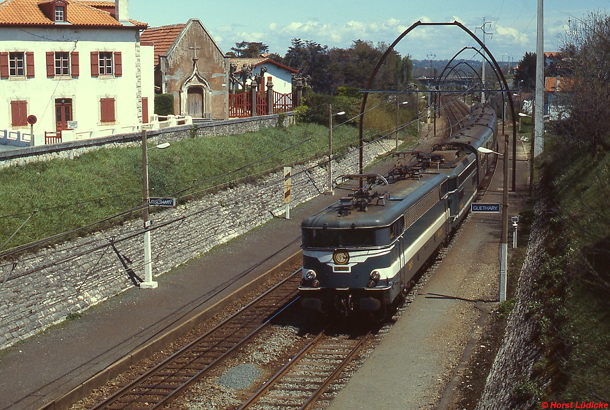 Mit einem Personenzug fährt eine BB9200-BB8600-Doppeltraktion im April 1986 in Guethary (Strecke Biarritz - Hendaye) ein. Die Gleichstromfahrmasten stammen noch aus der Zeit der Elektrifizierung in den 1920er Jahren.