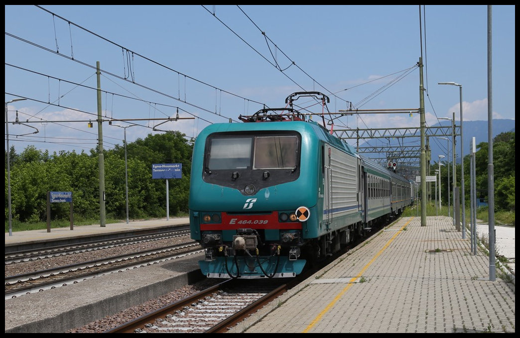 Mit einem Regionalzug aus Bozen fährt hier am 31.5.2022 die FS E 464.039 in Richtung Trento um 12.30 Uhr in den Bahnhof Egna / Neumarkt ein.