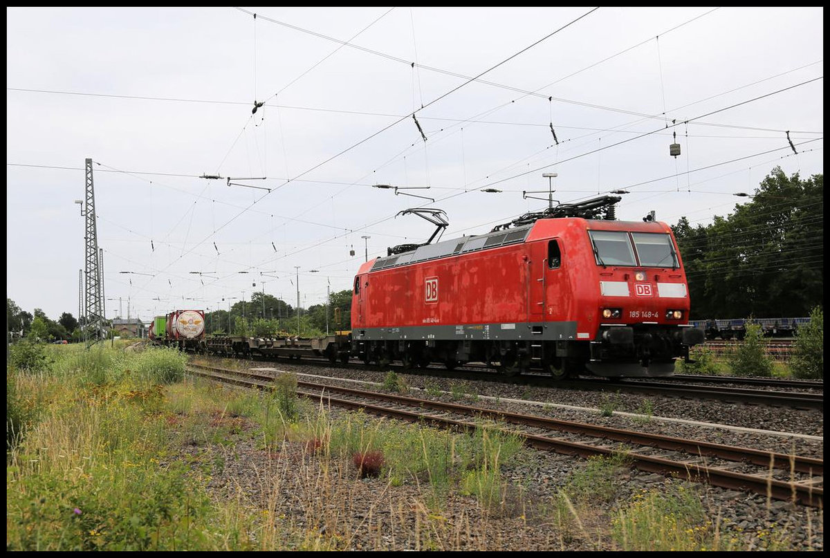 Mit einem roten Flickenteppich ist hier am 14.7.2020 die 185148-4 mit einem Containerzug auf der Rollbahn unterwegs. Um 14.12 Uhr kommt sie hier in Fahrtrichtung Münster durch den Bahnhof Hasbergen.