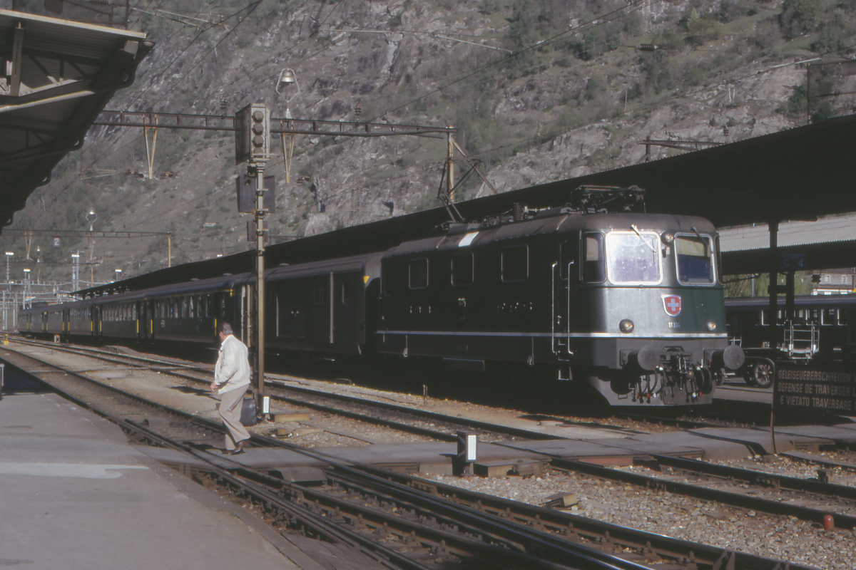 Mit einem Schnellzug nach Lausanne und weiter über die Jurafuß-Linie steht die Re 4/4 II 11314 am Abend des 29. April 1990 in Brig. Der Zug besteht aus den damals noch zeitgemäßen Einheitswagen II, hinter der Lok ist ein Gepäckwagen eingereiht. Lok und Wagen der SBB präsentieren sich in einem makellosen Zustand - so ist es auch heute.
Brig, 29.4.1990; Canon A1, Canoscan, Gimp 