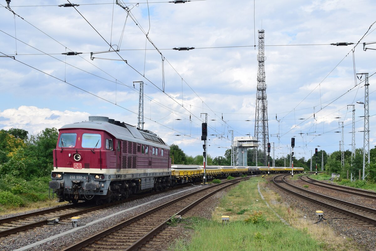 Mit einem Zug voller neuer Betonschwellen brummt 232 550-4 aus Königsborn kommend durch Biederitz in Richtung Elbbrücke. Die Lok erhielt bereits nach ihrer Übernahme bei der Bahnbaugruppe 2006 ihre Ursprungslackierung zurück.

Biederitz 19.07.2023