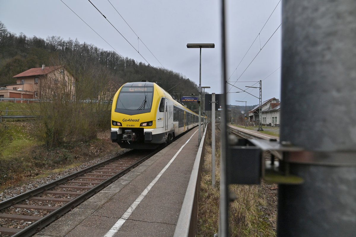 Mit gerade 40 Km/h kommt der GoAhead ET 6.09 als RE8 nach Würzburg durch Neudenau gen Osterburken gefahren. Da der Zwischenbahnsteig sehr eng ist gibt es in beide Richtungen diese Geschwindigkeitsbeschränkung, nach dem Bahnhof wird die Geschwindigkeit wieder auf 100Km/h angehoben, die Segmentstücke des Andreaskreuz samt Mast habe ich mit Absicht mit ins Bild gebracht um zu verdeutlichen wie eng es hier am Bahnsteigzugang vom Bahnsteig Gleis 2 zugeht. 31.1.2021