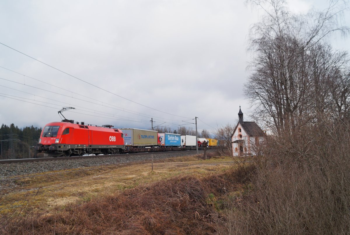 Mit einer gut ausgelasteten ROLA war 1016 033 am Vormittag des 07.03.2020 bei Brixlegg zum Brenner unterwegs und passierte im Frühlingsgrau die Hagauer Antoniuskapelle.