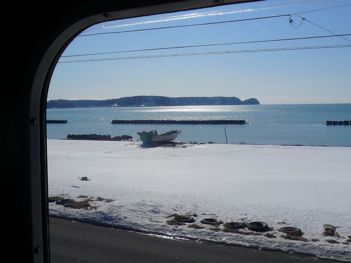 Mit der Hanasaki-Linie, der östlichsten Bahnlinie Asiens, ans Meer: Ein Boot wartet auf den Sommer in der Bucht von Akkeshi. Auf Triebwagen KIHA 54 519, 19.Februar 2009. 