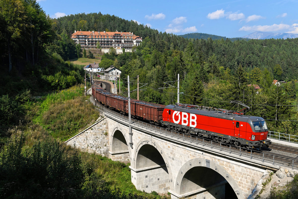 Mit ihrem kurzen Schrottzug benötigte die 1293.077 am 22. September 2020 keine zusätzliche Unterstützung, um den Semmering-Pass zu überwinden. Bei Wolfsbergkogel ist der Scheitelpunkt der Strecke bald erreicht. Auch wenn der Semmering-Basistunnel der Vollendung entgegenschreitet, hat man in den letzten Jahren einiges in den Erhalt der über 150 Jahre alten Gebirgsstrecke investiert. Diverse Bauwerke wurden saniert, so auch im Jahre 2017 der Kartnerkogel Viadukt, den der ÖBB Vectron auf dem Bild gerade überquert. 